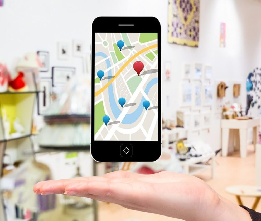 composite of hand holding smartphone with maps graphic with store background